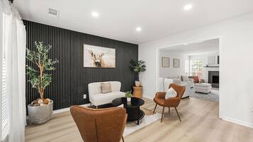 Un salon moderne avec un canapé, une table basse et des fauteuils, un mur d’accent noir et une cheminée en arrière-plan.