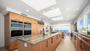 A modern kitchen with built-in ovens, a large island, and a view of the ocean. - 3 Story Single Family Home with Sauna, AC, and Private Gated Parking (Long Beach)