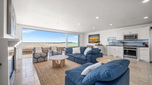 A spacious living area with a large window, a kitchen with white cabinets, and a view of the desert. - 3 Story Single Family Home with Sauna, AC, and Private Gated Parking (Long Beach)