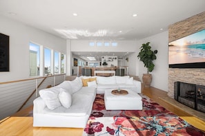 A modern living room with a sectional sofa, a fireplace, and a large window. - Panoramic Ocean Views with Sauna, AC, and Parking (Long Beach)
