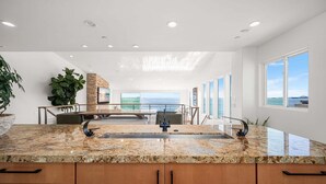 A modern kitchen with granite countertops, a built-in stove, and a large window overlooking the ocean. - 3 Story Single Family Home with Sauna, AC, and Private Gated Parking (Long Beach)