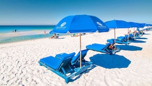 A beach with blue umbrellas and lounge chairs, a clear sky, and the ocean in the background. - Luxe Gulf-front Free Beach Chairs Balcony View Resort Amenities ON THE Beach (Panama City Beach)