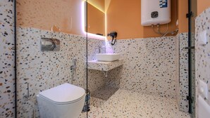 A modern bathroom with a freestanding toilet, a sink with a mirror, and a shower area. - Grandstay Studio 110 (Durrës)