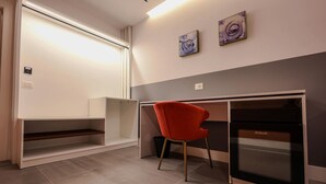 Ein modernes Zimmer mit einem roten Sessel, einem eingebauten Backofen und zwei abstrakten Bildern an der Wand.