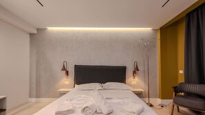 Ein modernes Hotelzimmer mit einem großen Bett, zwei Nachttischen, einer Stehlampe und einem Sofa.