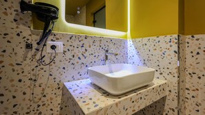 Ein Badezimmer mit einem weißen Waschbecken, einem an der Wand montierten Föhn und einem Spiegel über dem Waschbecken.