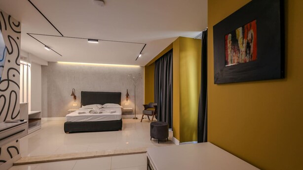Ein modernes Schlafzimmer mit einem großen Bett, Nachttischen, einem Sessel und einem Bild an der Wand.