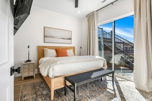 Un dormitorio con cama, mesita de noche, lámpara y vistas a una escalera.