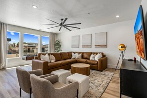 Una sala de estar moderna con un sofá modular, sillones, una mesa de centro y un televisor de pantalla plana.