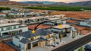 A residential area with modern houses, a road, and distant mountains. - Pecan Valley Retreat Sleeps 58| 2 Private Pools & Pickleball Courts (Hurricane)
