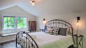 Una camera da letto con un letto, una cassettiera, un comodino e una finestra vista alberi.