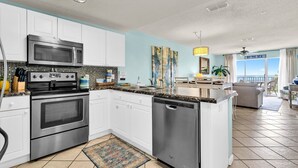 A modern kitchen with white cabinets, stainless steel appliances, and a large island.