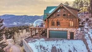 A log cabin with a stone garage, a covered porch, and a view of mountains.