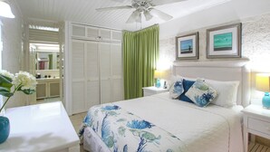 A bedroom with a bed, a nightstand, a dresser, a ceiling fan, and a green curtain.