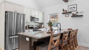 A modern kitchen with white cabinets, stainless steel appliances, and a granite countertop.