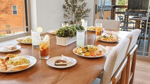 Une table à manger dressée avec différents plats, des boissons et une plante en pot.