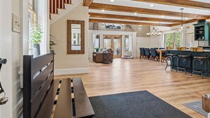 A spacious interior with a wooden staircase, a dining area with bar seating, and a kitchen area. - Moose Ridge Haven | Spacious and beautifully appointed home | Hot tub & Sauna (Rangeley)