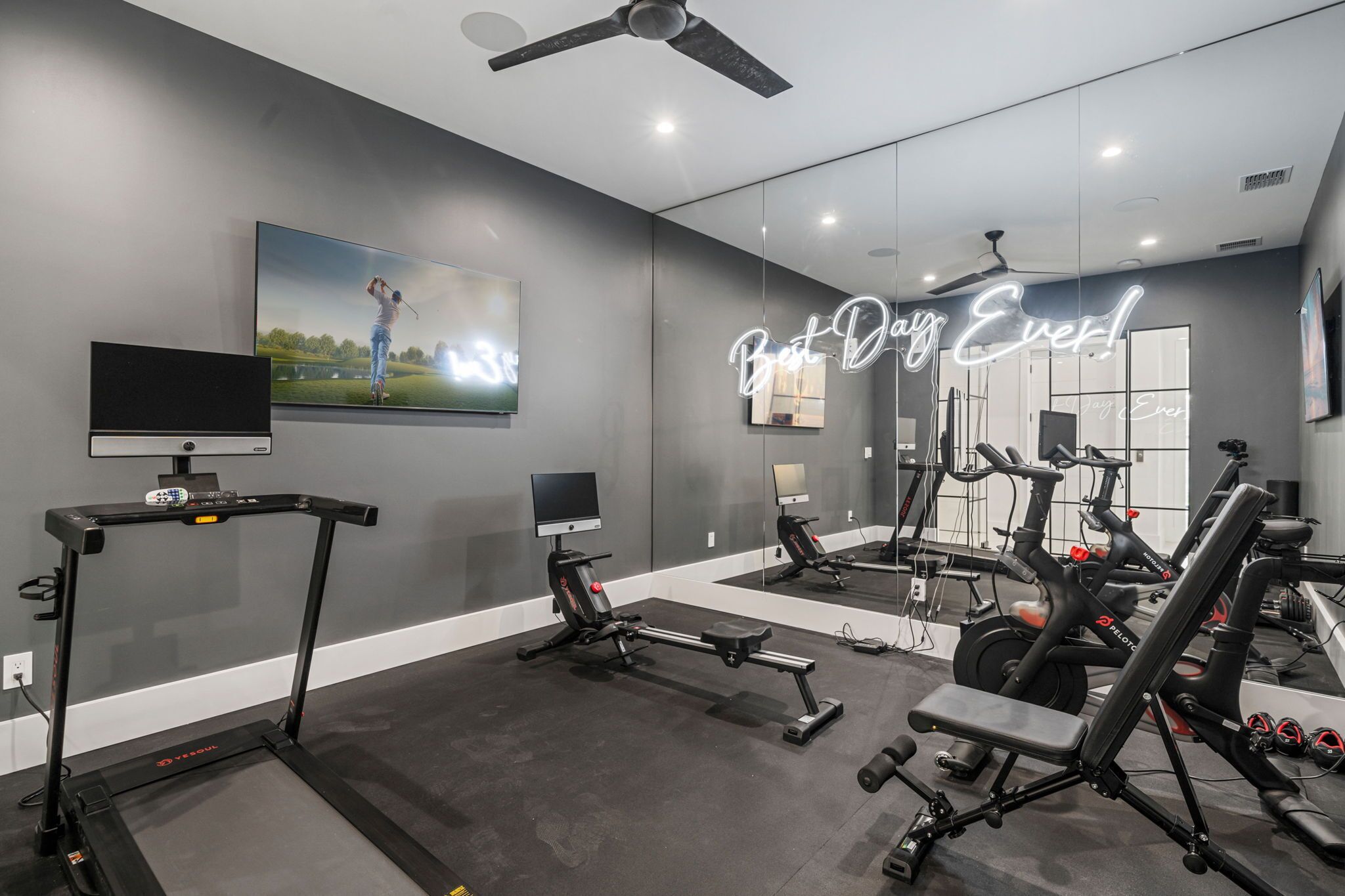 A modern gym with exercise equipment, a treadmill, and a large mirror.