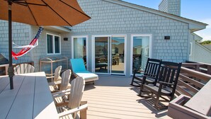 Une terrasse dotée de mobilier d’extérieur, comprenant des chaises et une table, ainsi qu’un grand parasol.