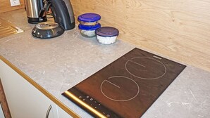 A kitchen with a built-in induction cooktop, a coffee maker, a kettle, and containers on a marble countertop. - Nice apartment for 3 people with WIFI, TV and terrace (Wenns)