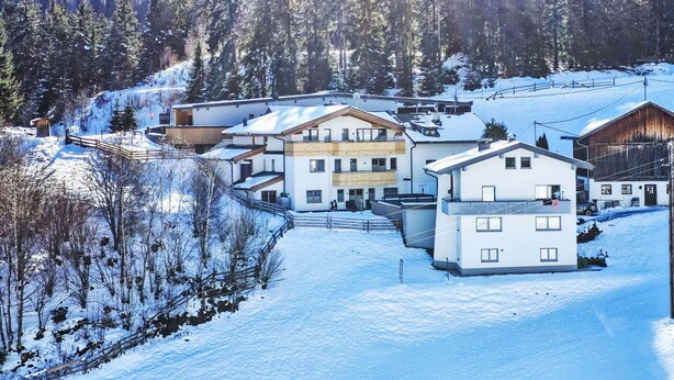 A snow-covered residential area with modern buildings, a ski lift, and a forested backdrop. - Nice apartment for 3 people with WIFI, TV and terrace (Wenns)