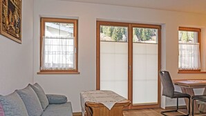A cozy living room with a grey sofa, a wooden coffee table, a chair, and a sliding glass door leading to a balcony. - Nice apartment for 3 people with WIFI, TV and terrace (Wenns)