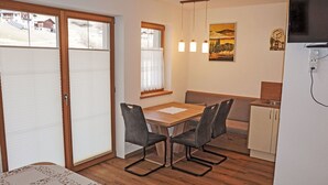 A compact kitchen with a dining area, wooden flooring, and a TV mounted on the wall. - Nice apartment for 3 people with WIFI, TV and terrace (Wenns)