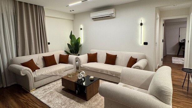 A modern living room with a sectional sofa, a coffee table, and a large plant.
