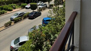 A residential street with parked cars, palm trees, and multi-story buildings.