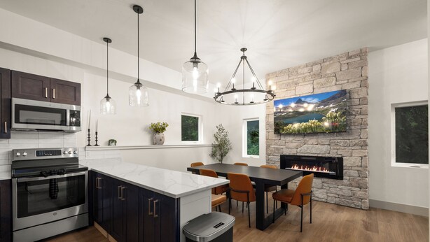 A modern kitchen with a stone fireplace, a dining area, and a large window.