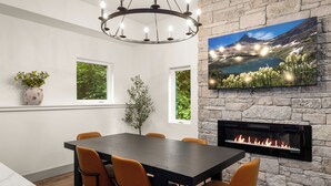 A dining area with a stone wall, a fireplace, and a TV mounted above it.