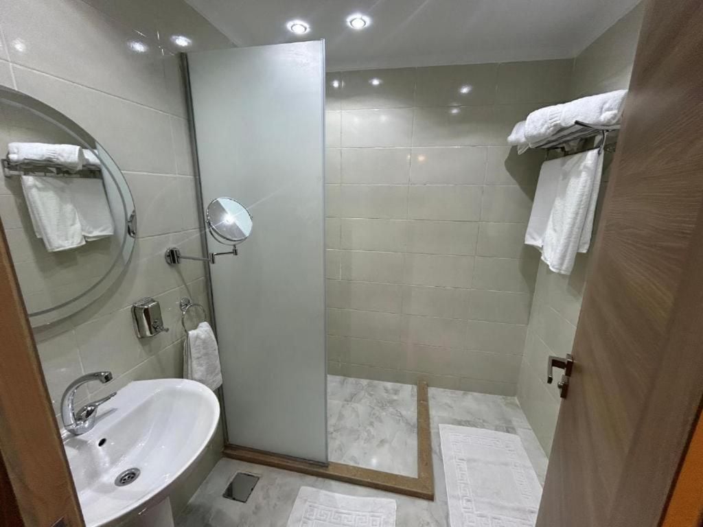 A modern bathroom with a glass shower enclosure, a sink, and a mirror.