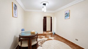 Un pasillo de hotel con una mesa redonda, sillas, un cesto de basura y una puerta que da a otra habitación.