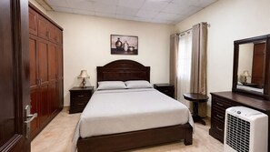 A bedroom with a bed, a nightstand, a dresser, a mirror, a heater, and a painting on the wall. - Skyline Luxury Suites (Cairo)
