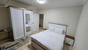 A bedroom with a bed, a wardrobe, a nightstand, and a bedside table.