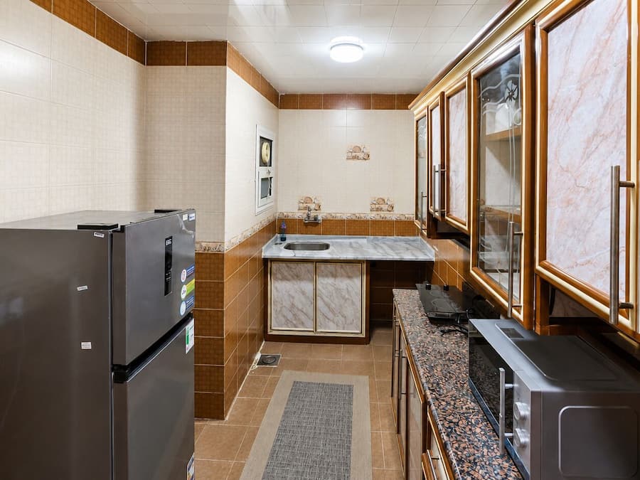 Una cocina compacta con refrigerador, pileta y alacenas.
