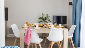 Ein moderner Essbereich mit einem Holztisch, weißen Stühlen und Frühstücksangeboten.