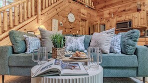 A cozy wooden interior with a sofa, a clock, and a book on a table.