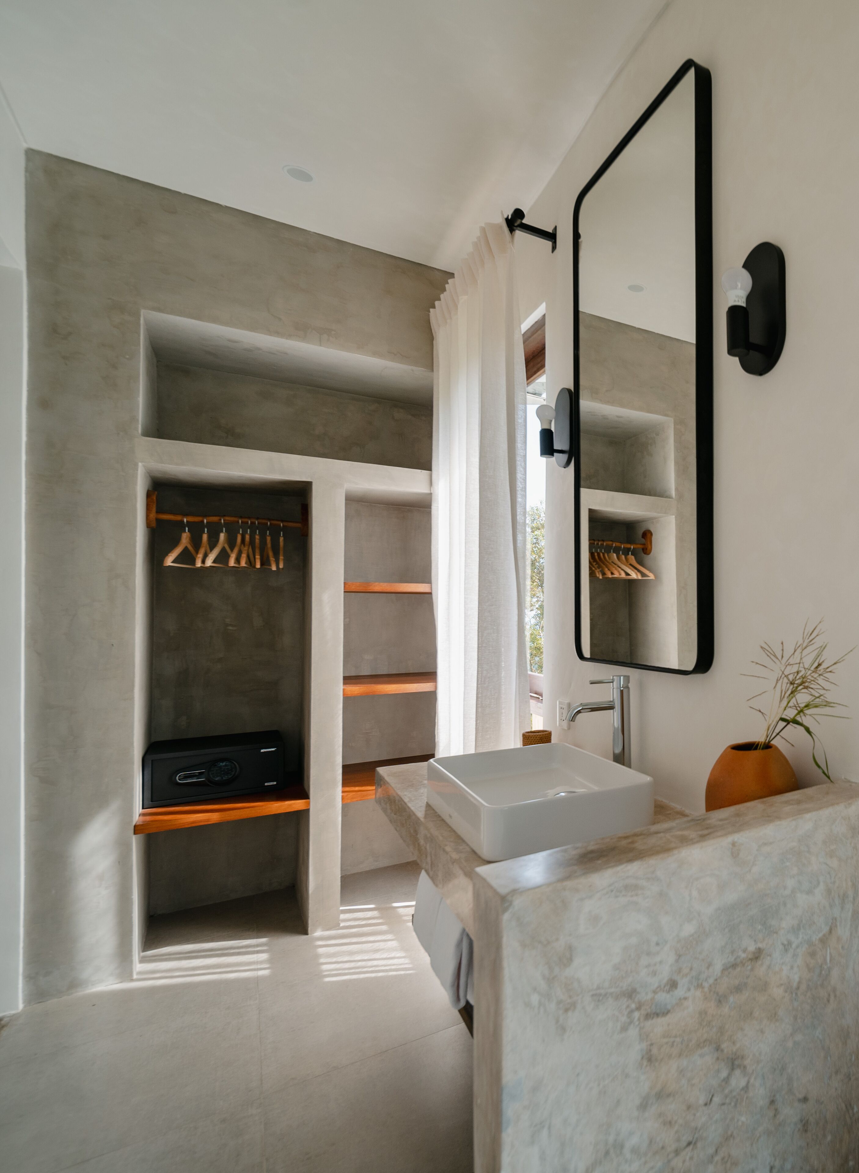 Un baño moderno con un espejo grande, estantes empotrados y un mueble de tocador con lavamanos.