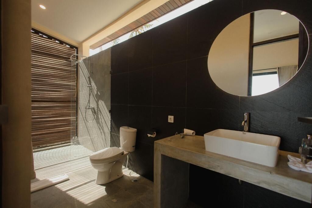 Een moderne badkamer met een grote spiegel, een wastafel en een toilet.