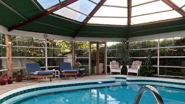 Ein überdachter Pool mit Liegestühlen und einer Glaskuppel.