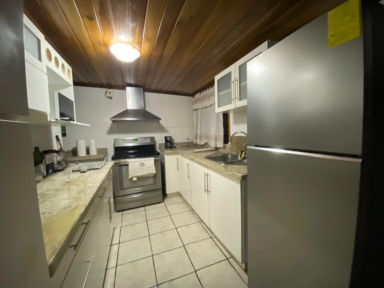 Una cocina con estufa, horno, pileta y alacenas.