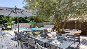 An outdoor patio with a dining table, chairs, and a large umbrella. - Villa du Sourdonnet by Interhome (Les Mathes)