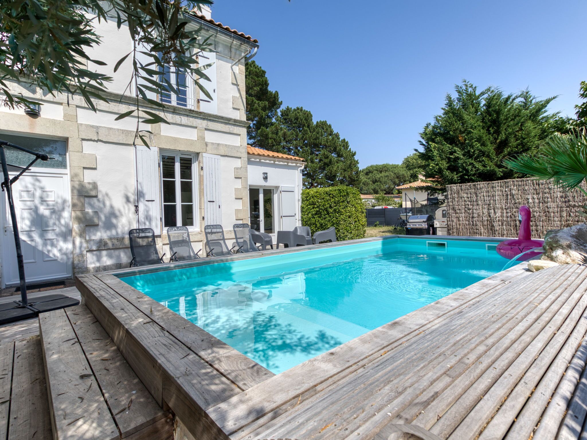 Une piscine avec des chaises longues et une terrasse en bois.
