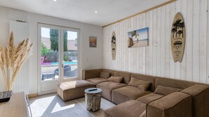 A modern living room with a large sectional sofa, a small round table, and a view of the outside. - Villa du Sourdonnet by Interhome (Les Mathes)