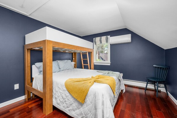 Un dormitorio con literas, una ventana con cortinas, una silla y un radiador.