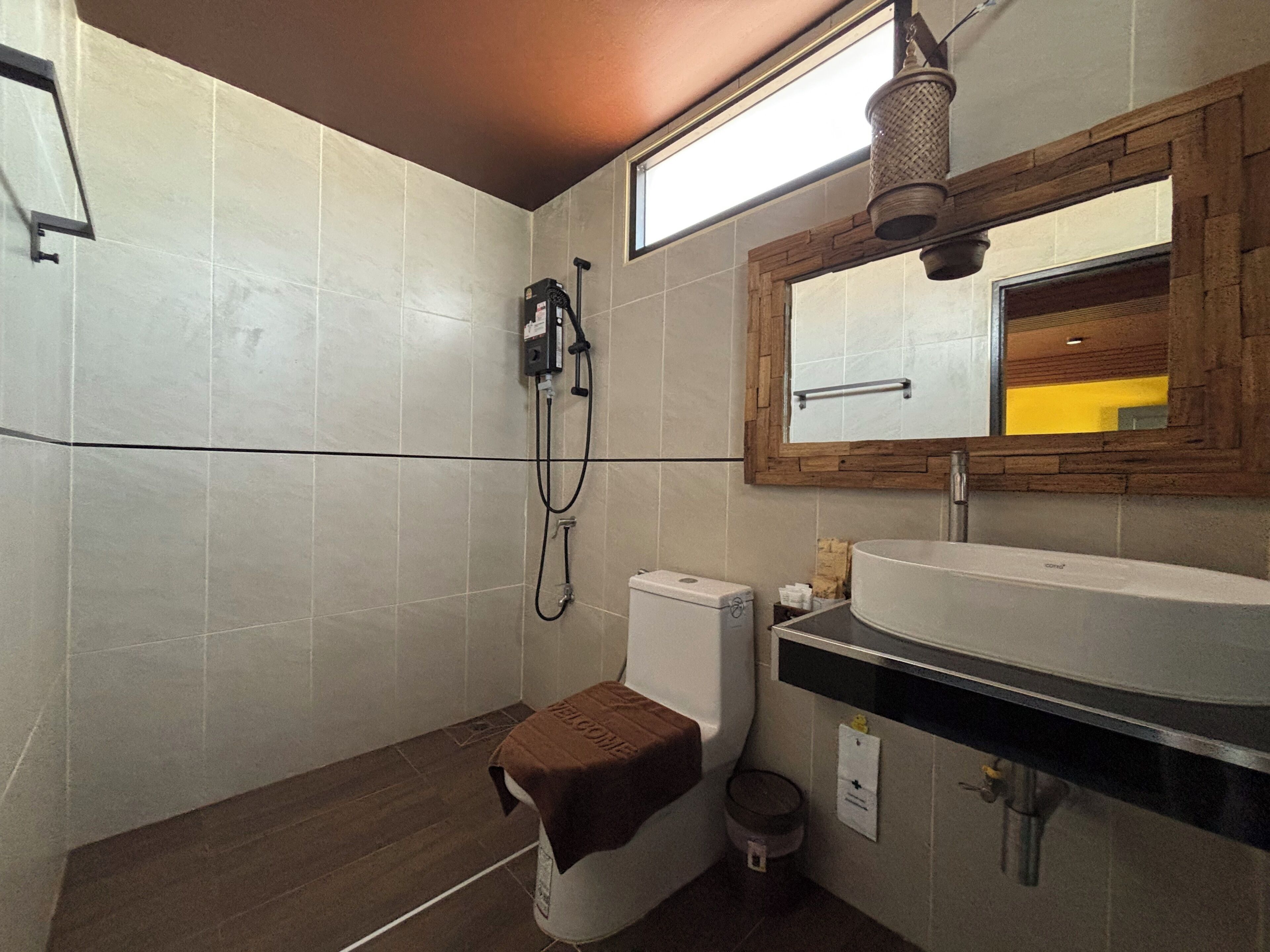 Un baño con ducha, inodoro, lavabo y espejo con marco de madera.