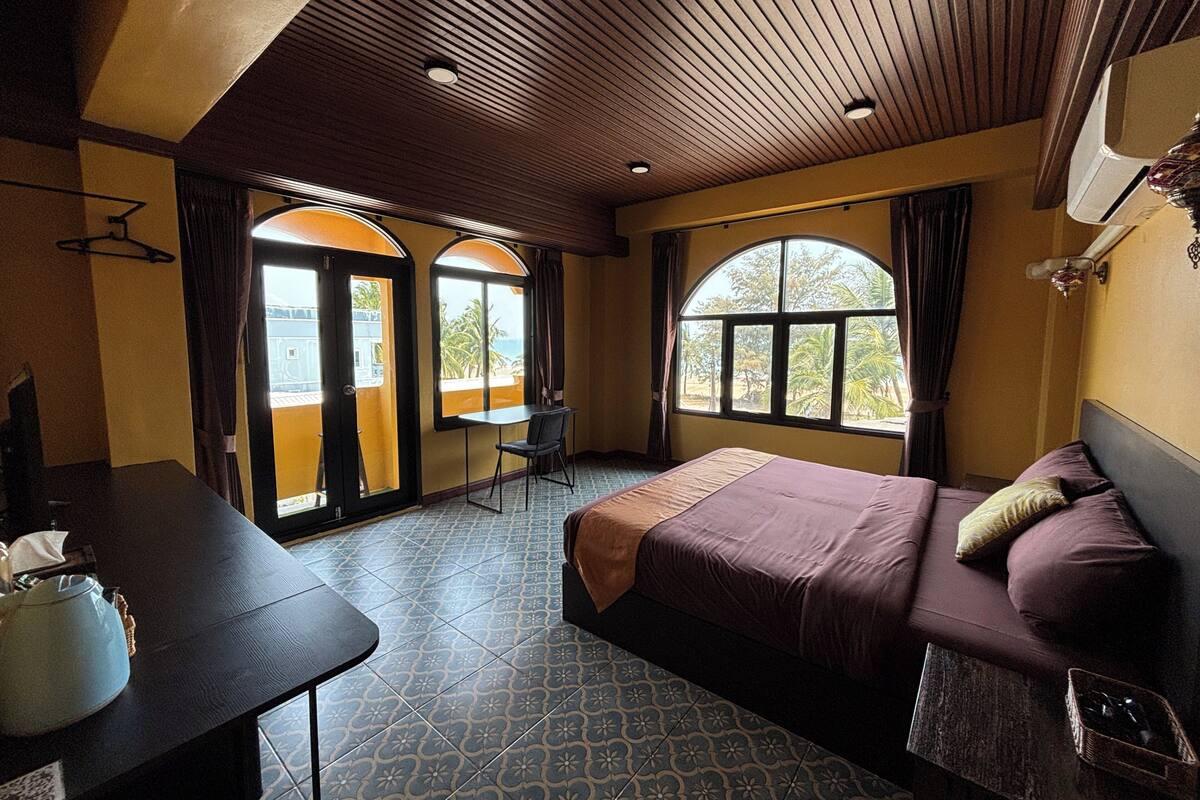 Une chambre d’hôtel équipée d’un lit, d’un bureau et de deux fenêtres donnant sur un paysage agréable.