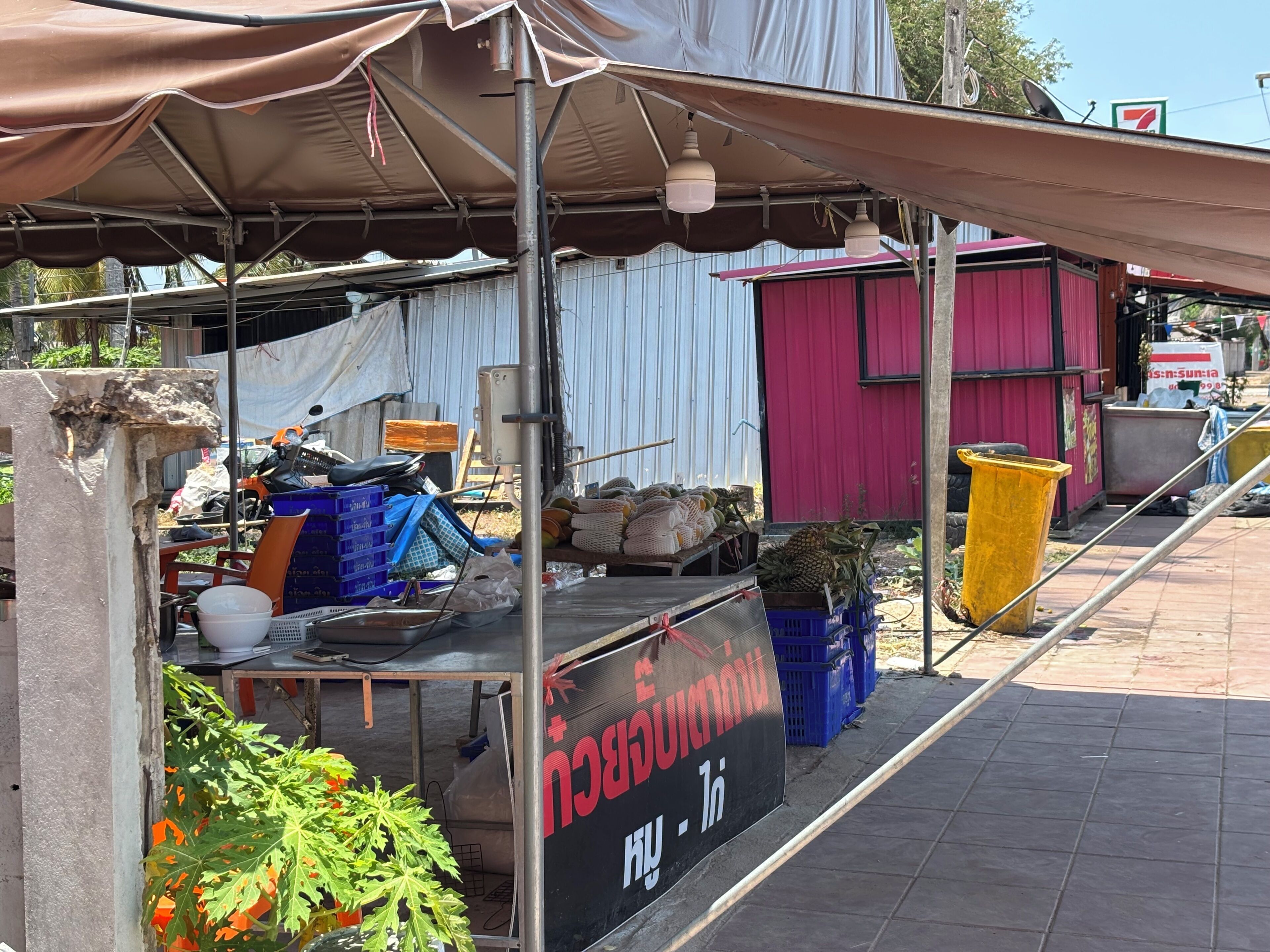 Ein Marktstand mit Schild, Kisten und Mülleimer.