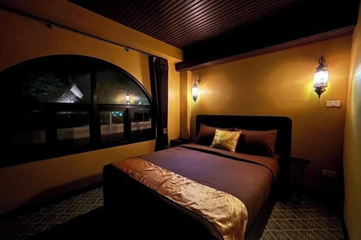 Une chambre à coucher avec un lit, une fenêtre et deux lampes fixées au mur.
